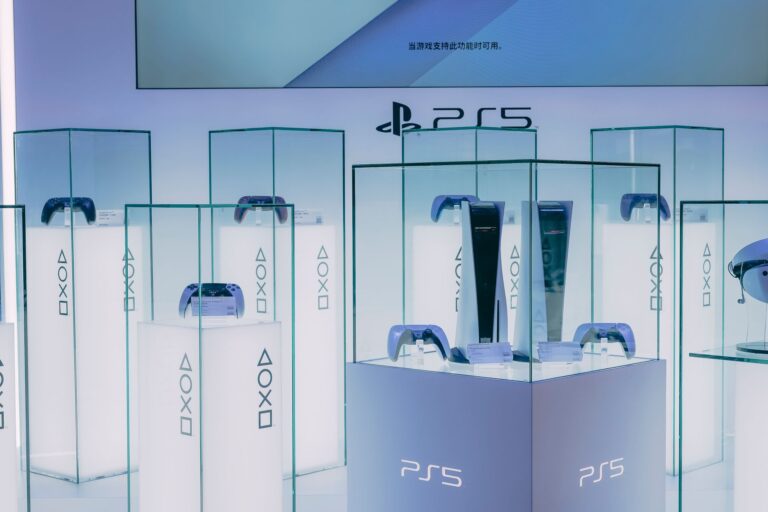 Vitrine PlayStation 5 avec consoles et manettes DualSense exposées, sous le logo PS5