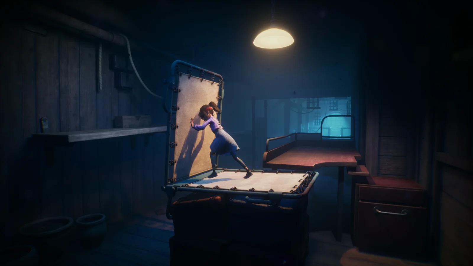 Une fillette pousse un sommier dans une pièce sombre éclairée par une lampe, dans le jeu Out of Sight offert sur l'Epic Games Store