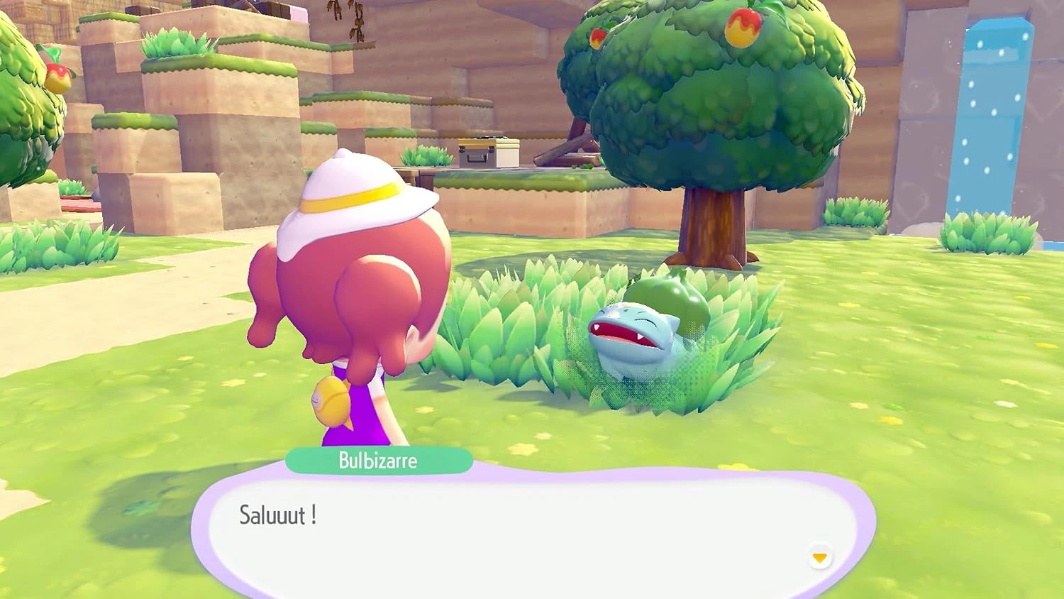 Le personnage de Pokémon Pokopia salue un Bulbizarre dans l'herbe, près d'un arbre à fruits